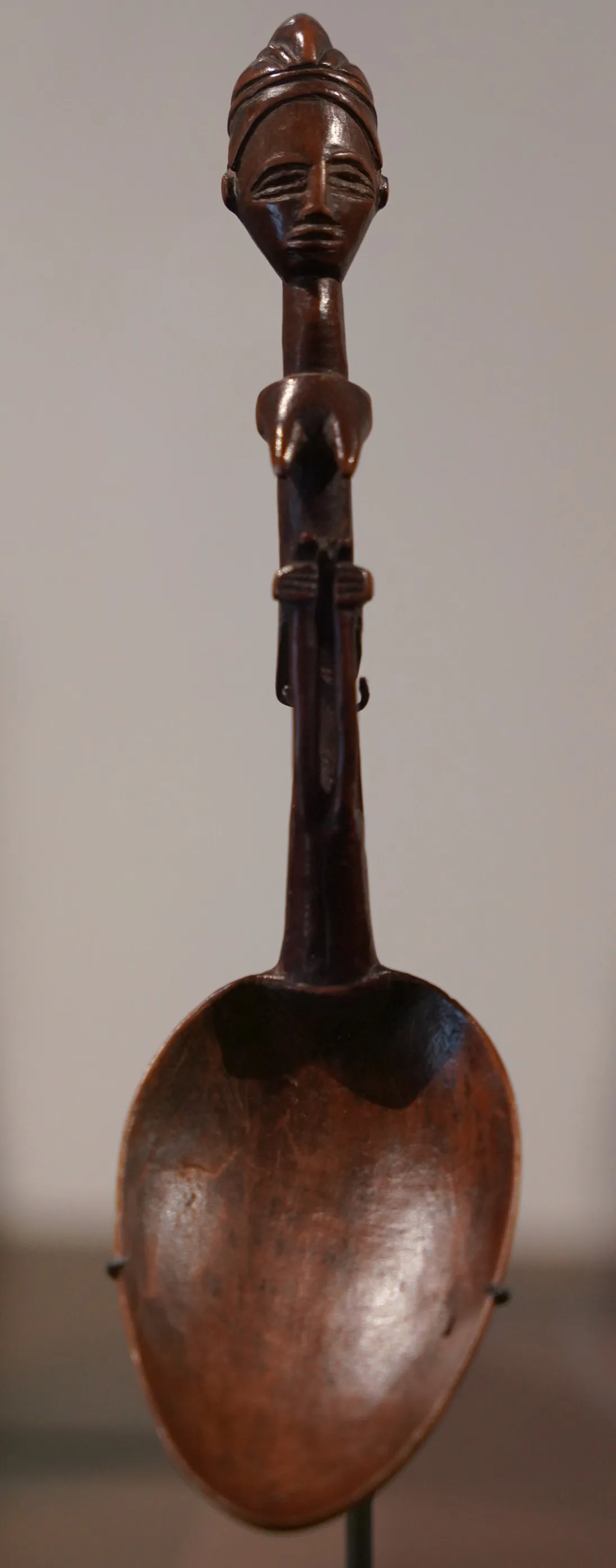 Cuiller de bois sombre au manche sculpté d’un personnage